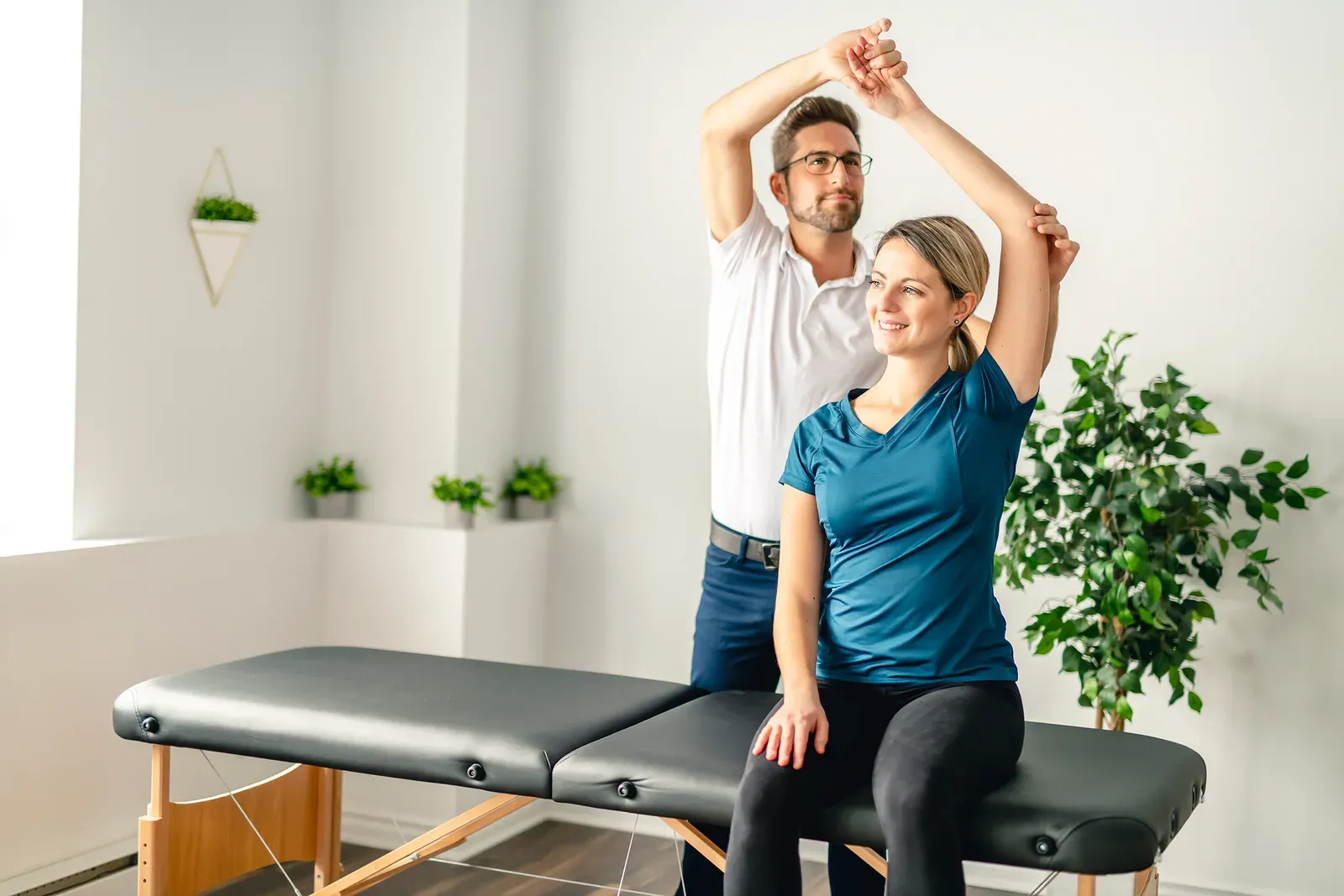 A practitioner guiding a client through an assisted stretch on a treatment table