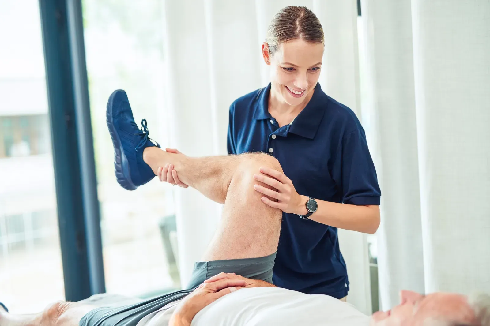 A practitioner guiding a client through a supported leg stretch on a treatment table