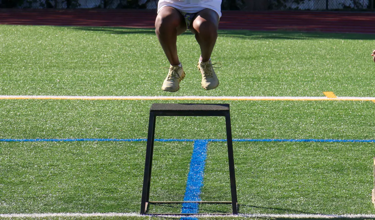 Young athlete performing a vertical jump test while a coach observes