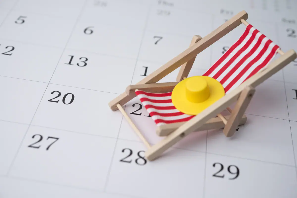 Red beach chair and hat on a blank calendar, a reminder to plan training space bookings around holidays