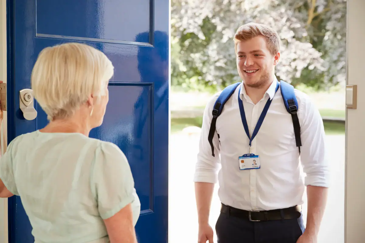Senior woman greeting a male care worker on a home visit, similar to a trainer arriving for an in-home session