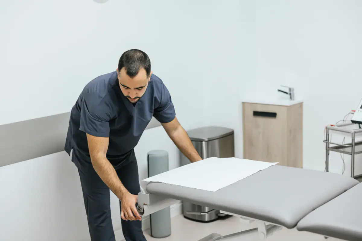 Physiotherapist preparing a treatment table for a patient session, similar to a portable adjusting table for a chiropractor