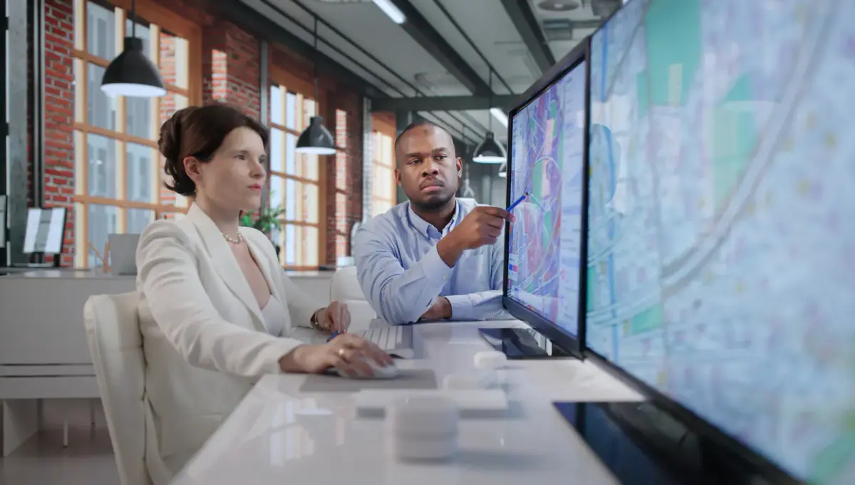 Two urban planners reviewing maps and data, a similar way to weigh a training location against where clients live