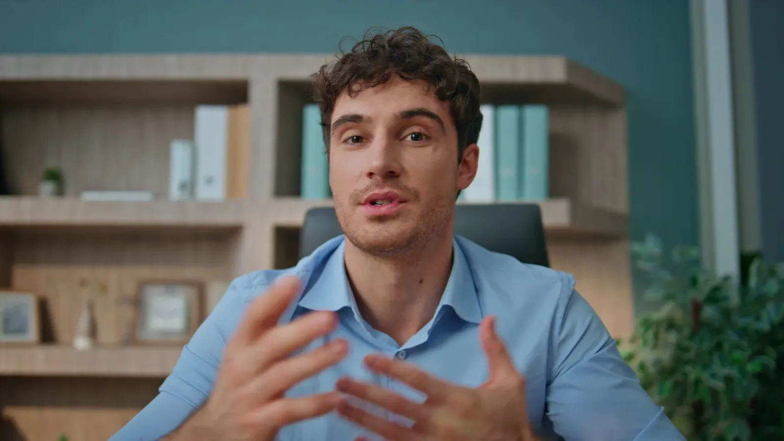 Online coach waving to the camera while recording a welcome video in an office