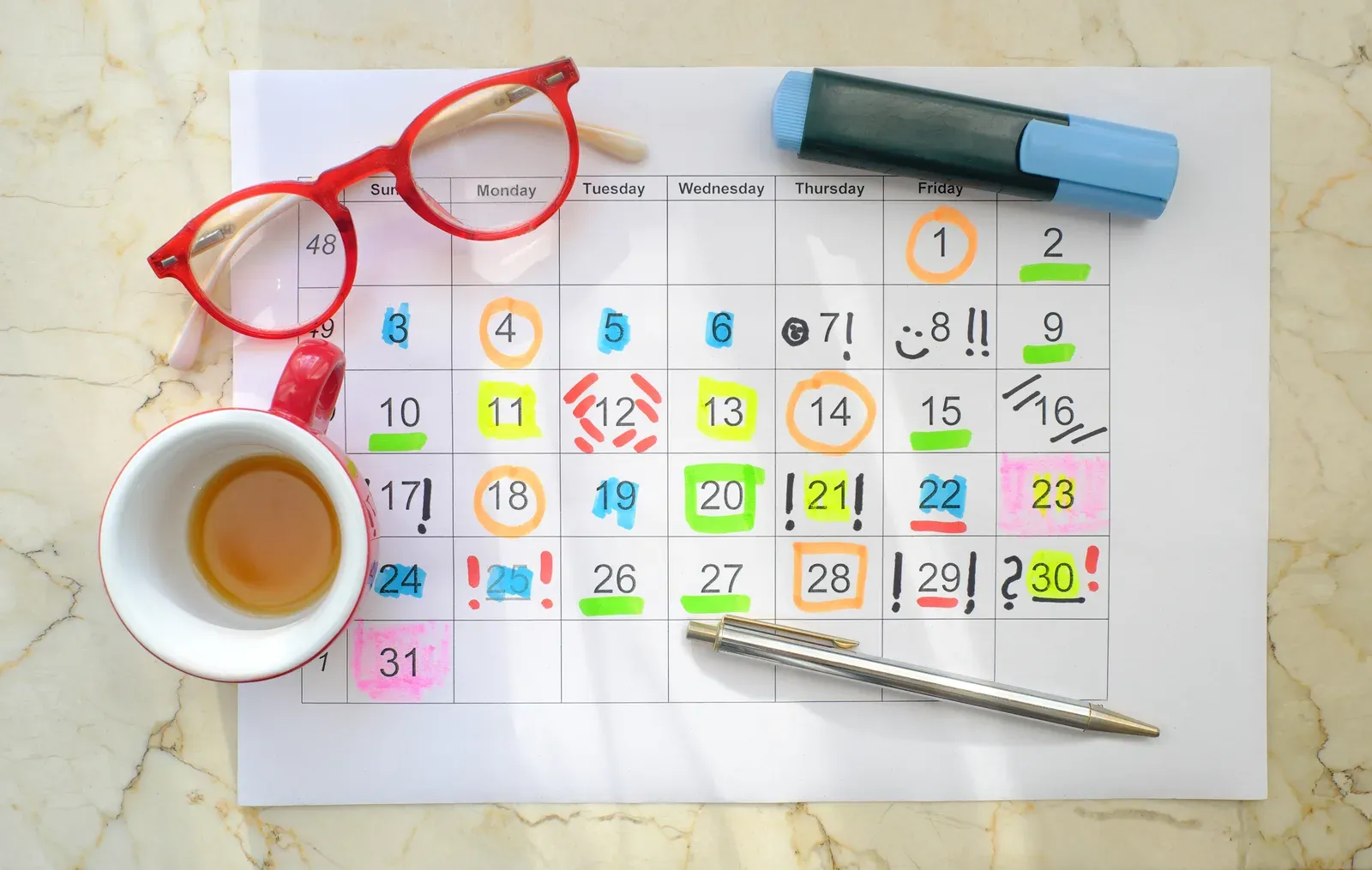 Calendar filled with appointments beside coffee and glasses, mapping a full-time client load