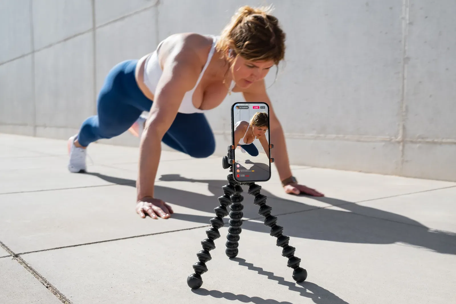 Fitness creator recording a workout on a phone set up in front of her