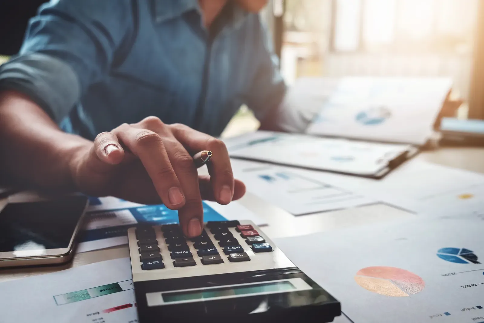 Working out corporate wellness pricing with a calculator, laptop and budget papers