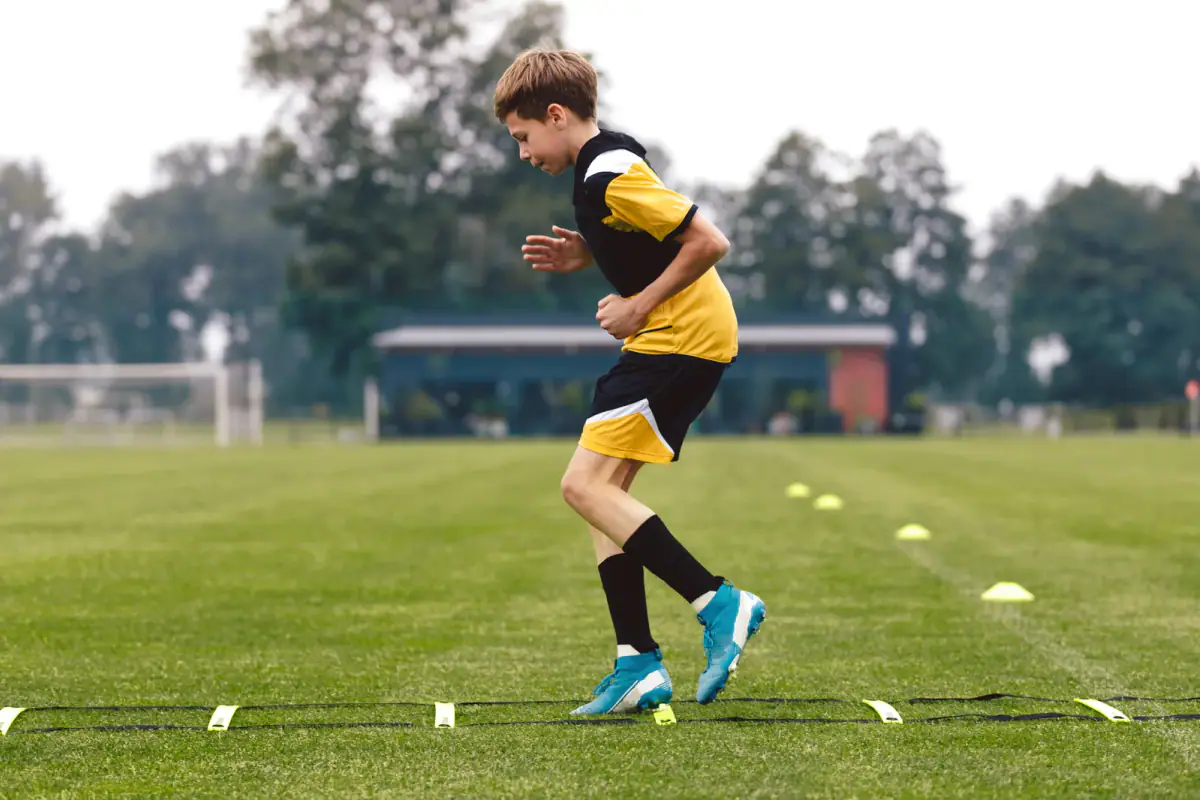 Junior football club player training on a soccer ladder, a simple piece of gear for youth athletic training