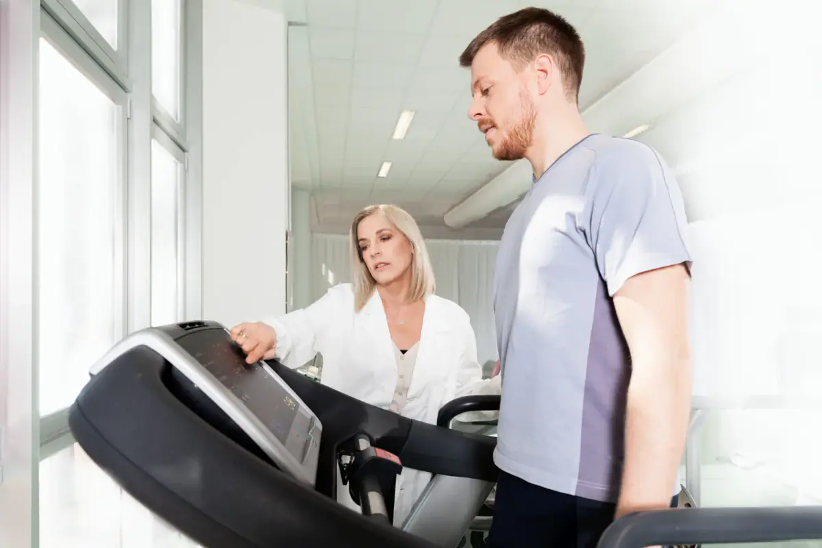 Athlete on a treadmill with a physiotherapist, a clinical setting to compare with exercise physiologist private practice
