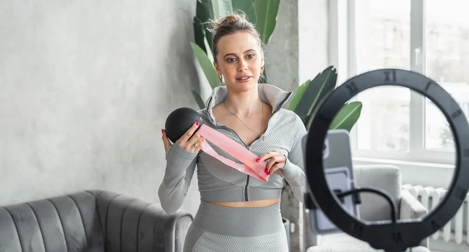Fitness coach recording an exercise demonstration on a camera in a gym