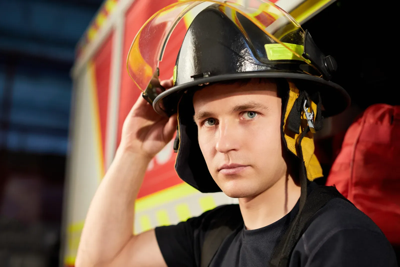 A firefighter holding his helmet in front of a fire truck