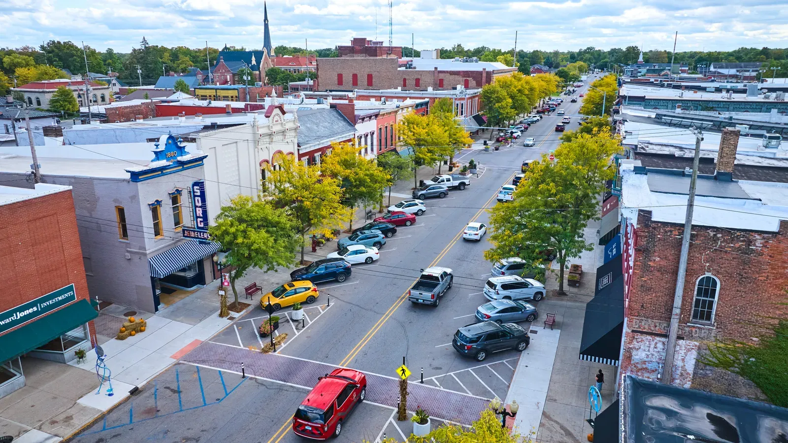 Aerial view of a tree lined suburban downtown street with shops and parked cars