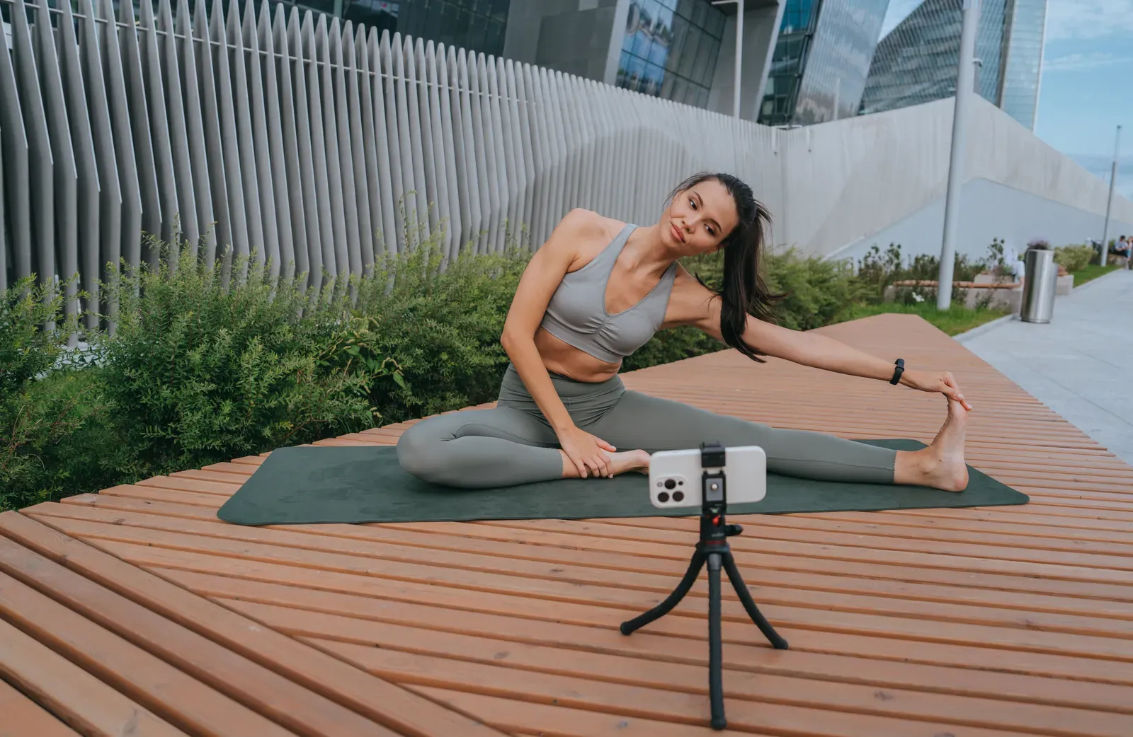 Fitness creator filming a workout with a phone mounted on a tripod