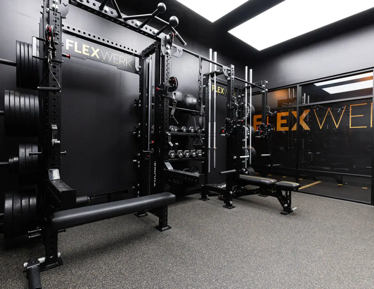 Lifting rack, barbells, and dumbbells lined up inside a private training room