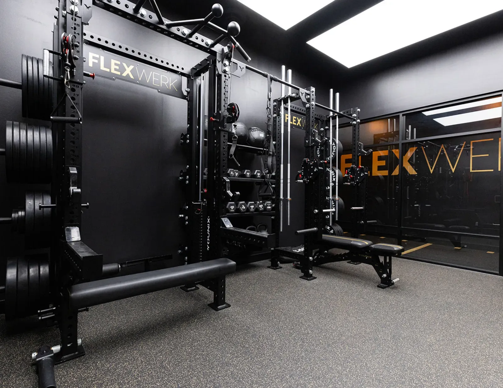 Lifting rack, barbells, and dumbbells lined up inside a private training room