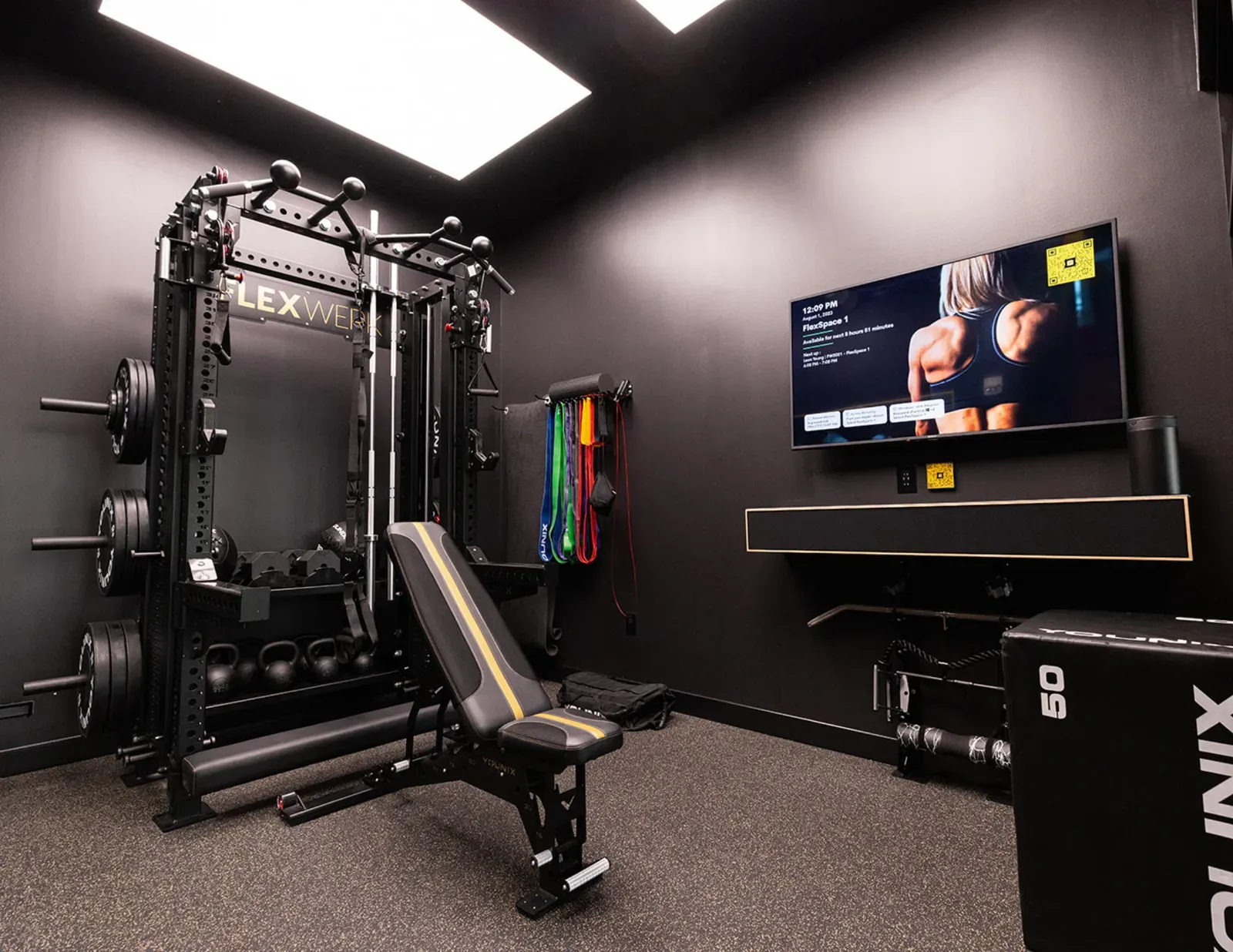 Fully equipped private workout space at FlexWerk Carmel with a lifting rack, bench, and dumbbells