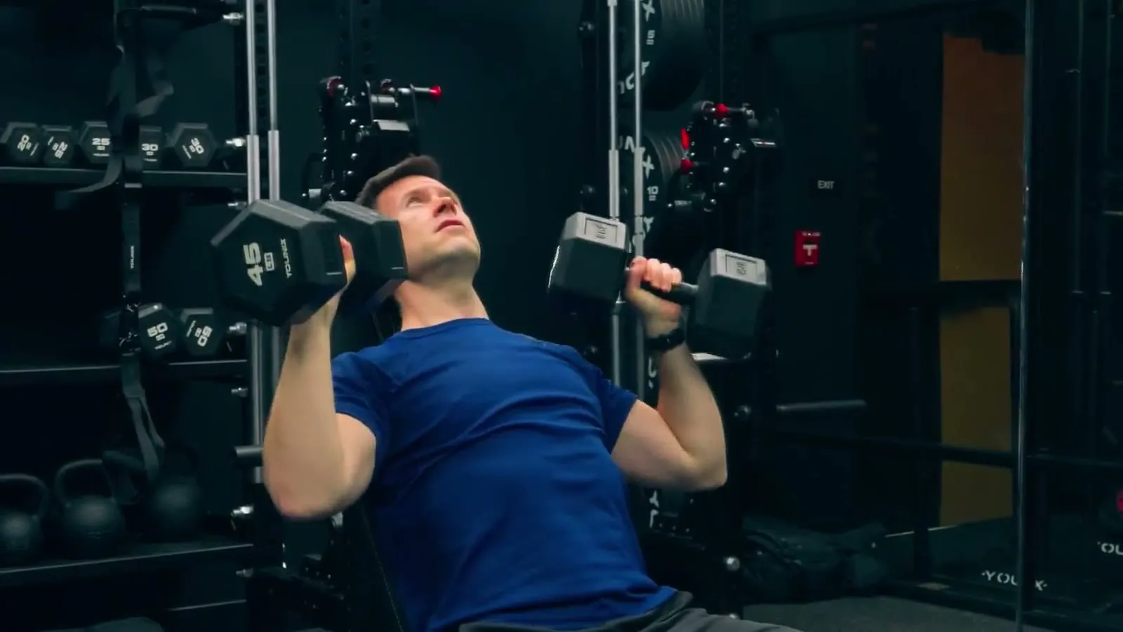 Pressing dumbbells on an incline bench inside a private FlexWerk space