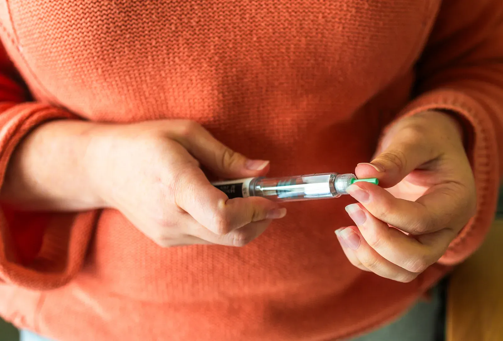 A person holding a medication injection pen at home