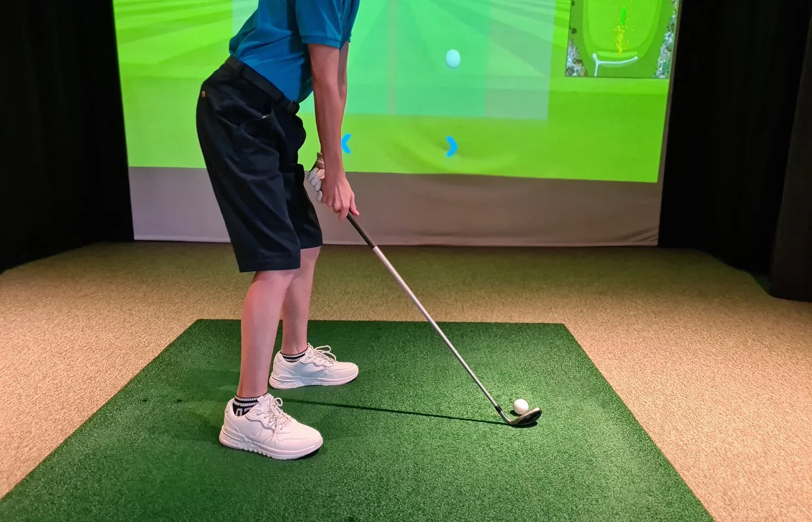 A golfer lining up a shot on an indoor golf simulator