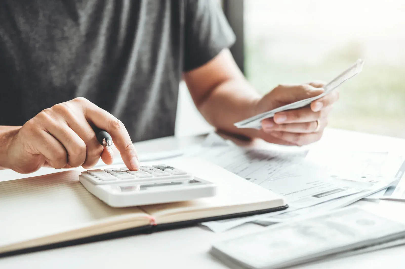 Man totaling bills on a calculator beside a growing stack of money