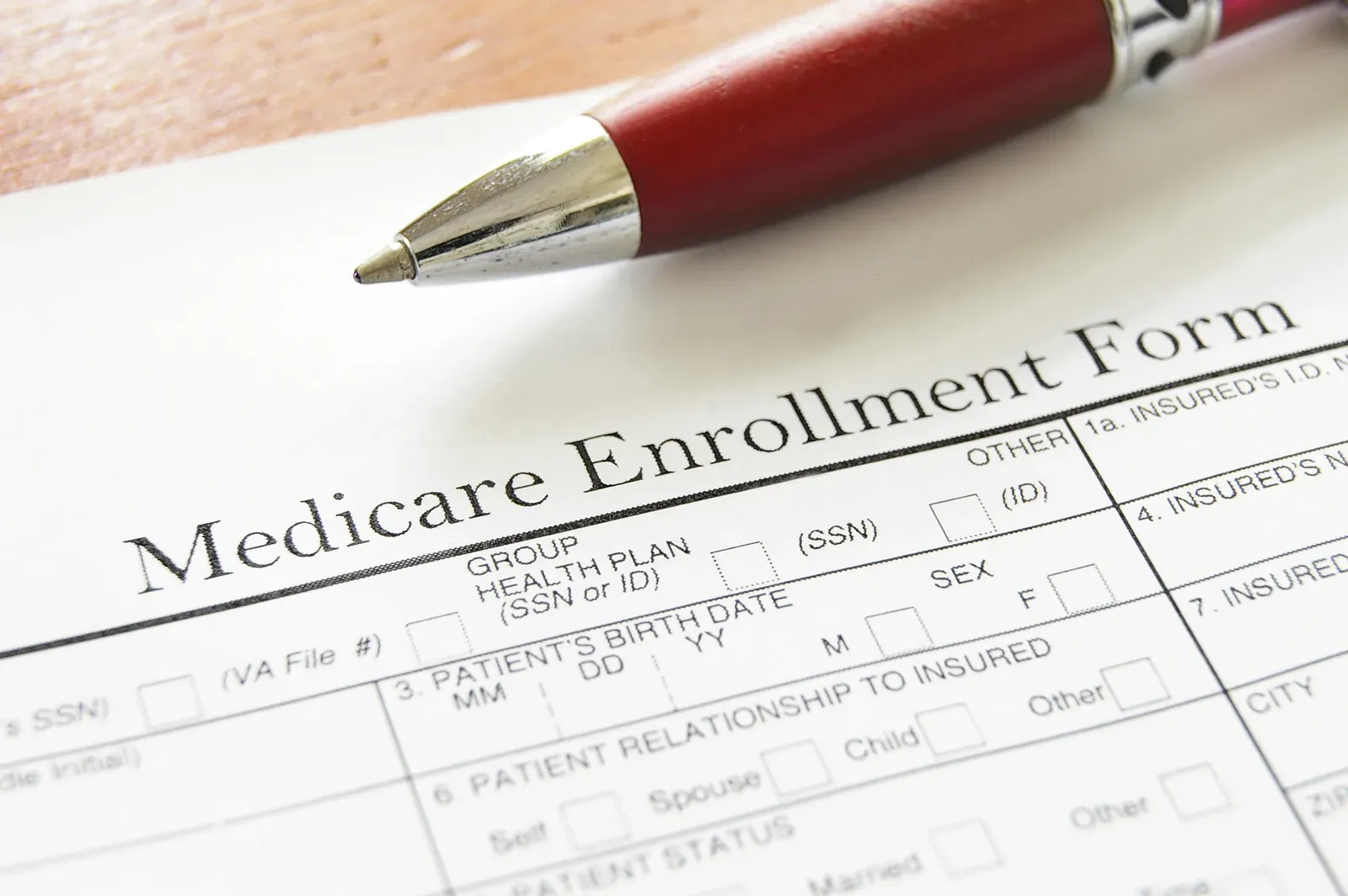 Medicare enrollment form with a red pen, one route to health coverage
