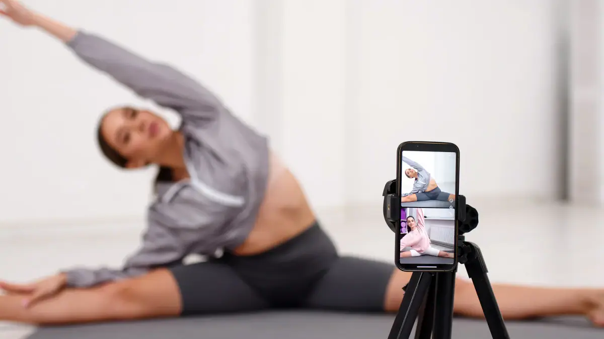 Female personal trainer leading a fitness session while filming a workout video, the work a hired photographer could capture