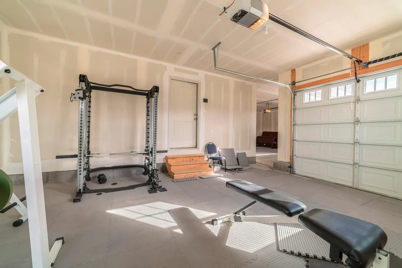 Garage converted into a home gym with a squat rack and weight plates