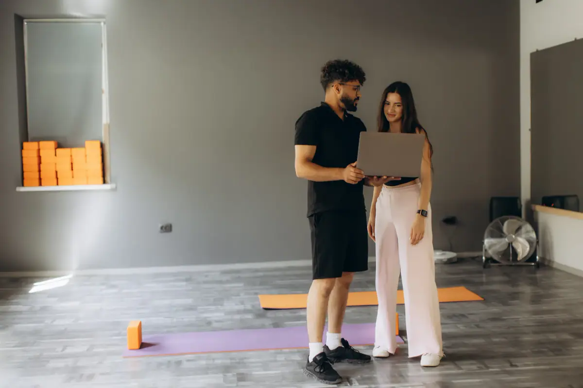 Fitness coach discussing a workout plan with a client, the paid time that hourly vs monthly studio rental has to cover