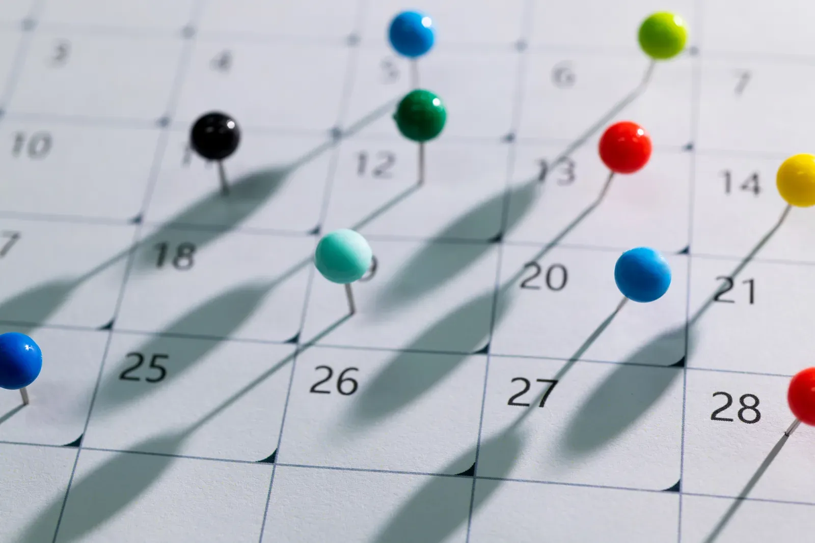 Colored pins marking a packed schedule on a calendar