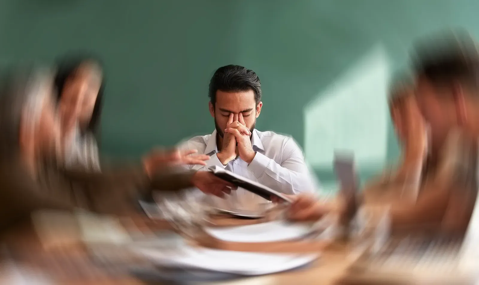 Stressed man in a meeting looking frustrated, facing a difficult client conversation