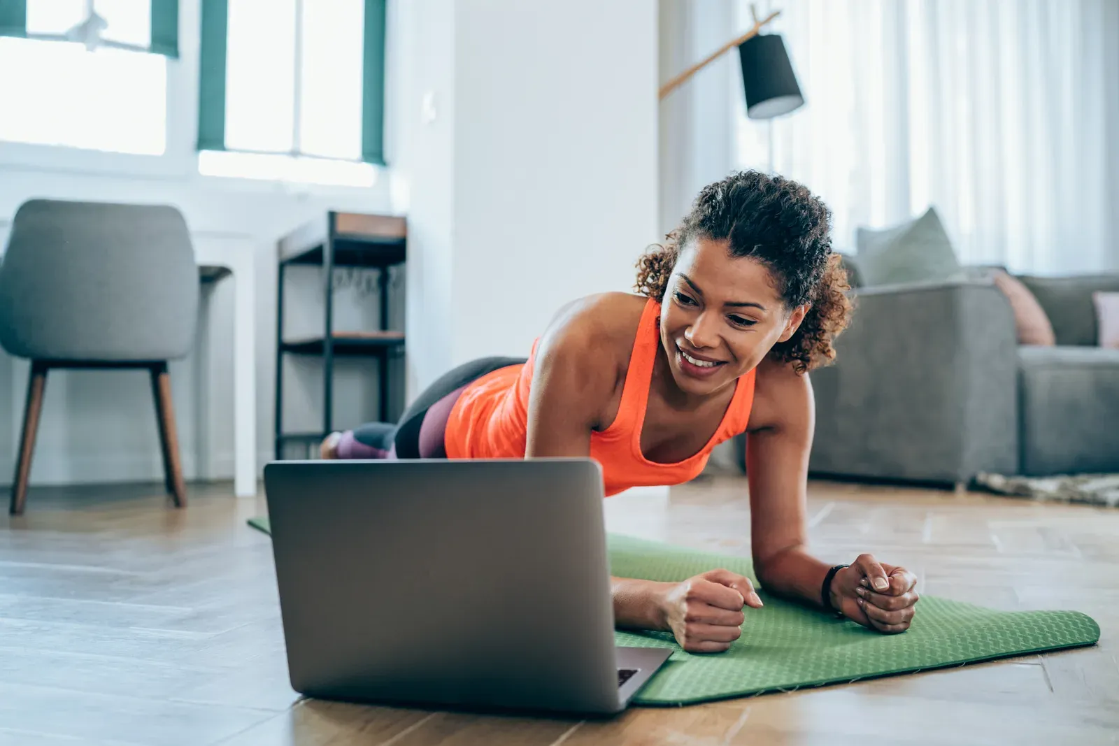 Woman exercising at home, the remote side of a hybrid coaching model
