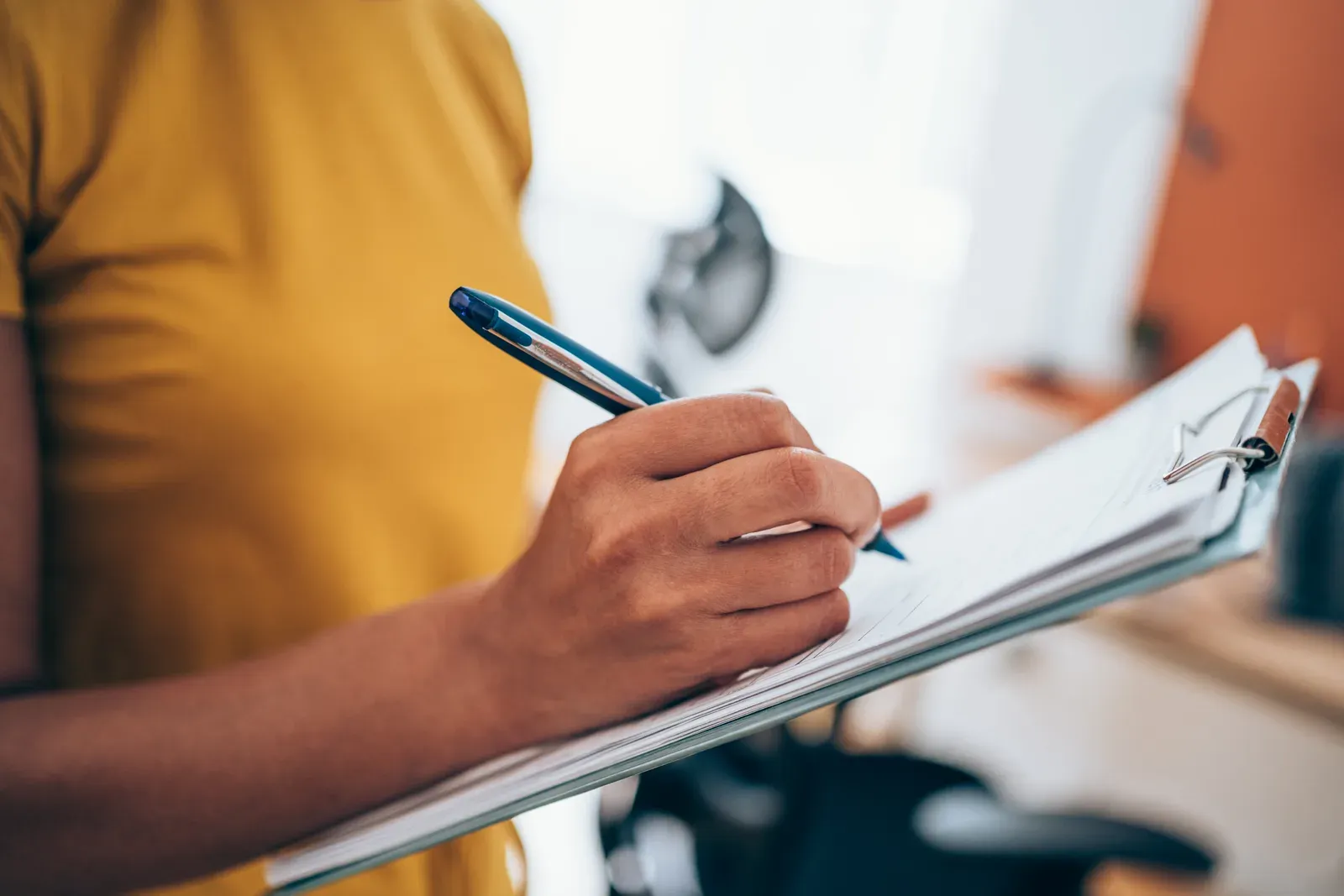 Hand filling out a clipboard form, drafting terms for a client contract
