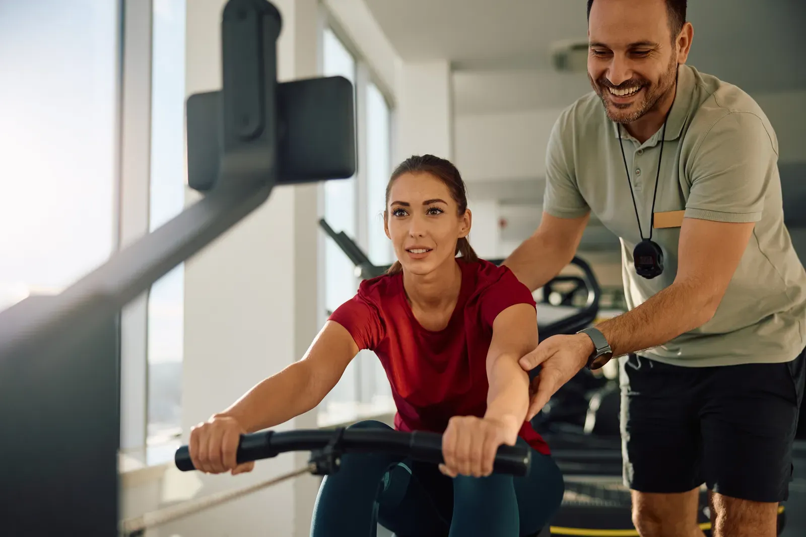A coach observing an athlete's stroke technique on a rowing machine