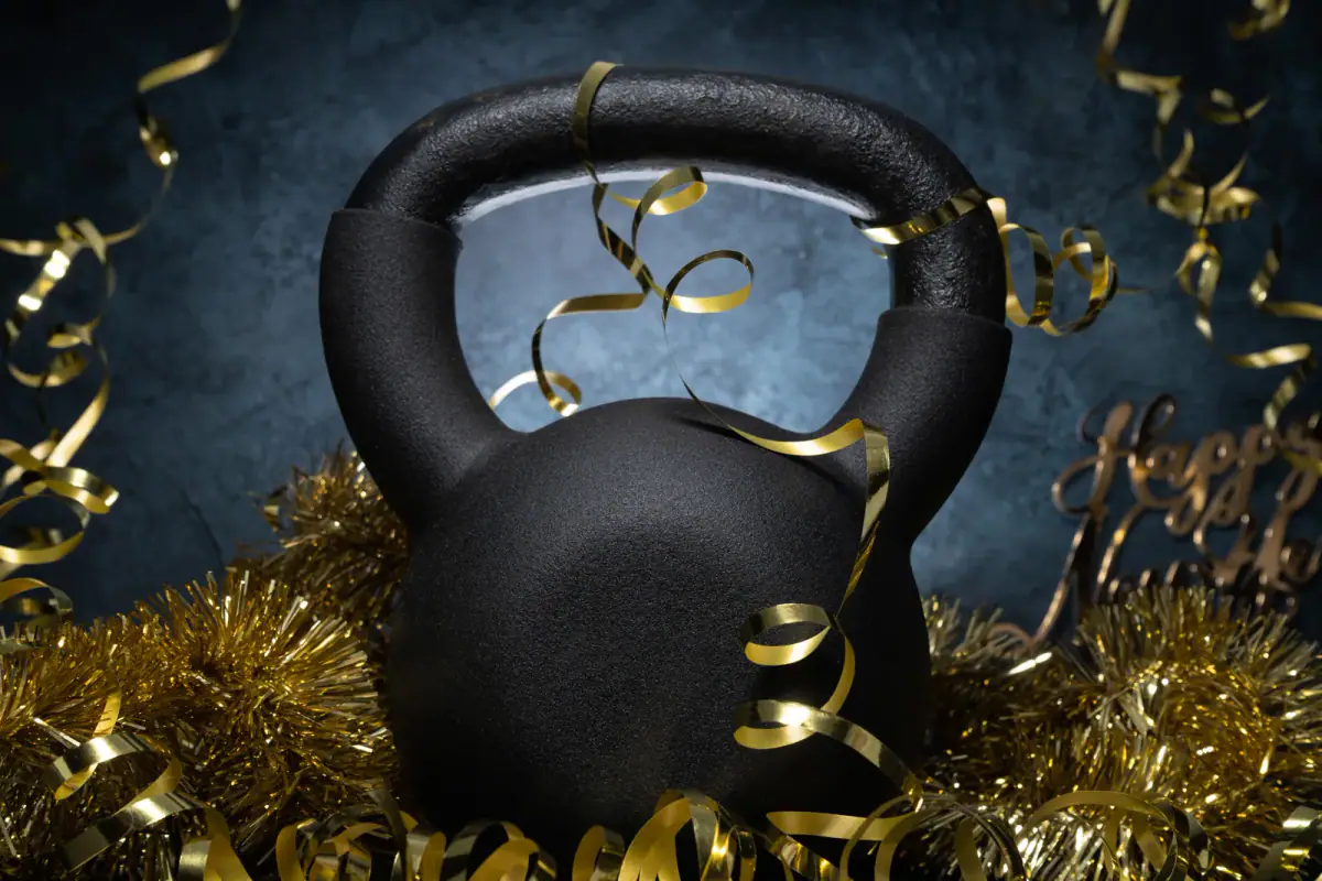 Kettlebell surrounded by golden New Year decorations, ready for January resolutions
