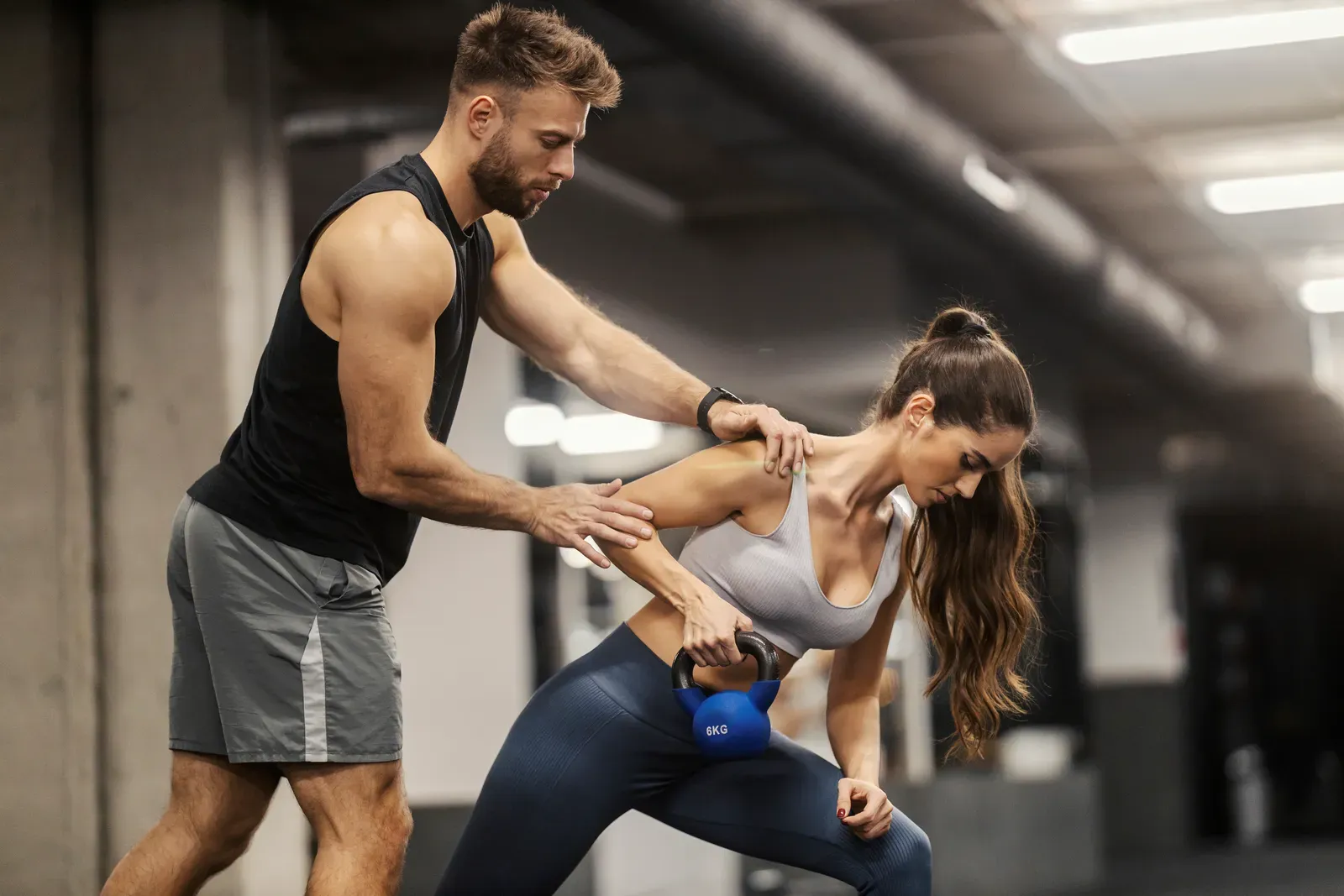 An instructor coaching a kettlebell swing at the top of the movement