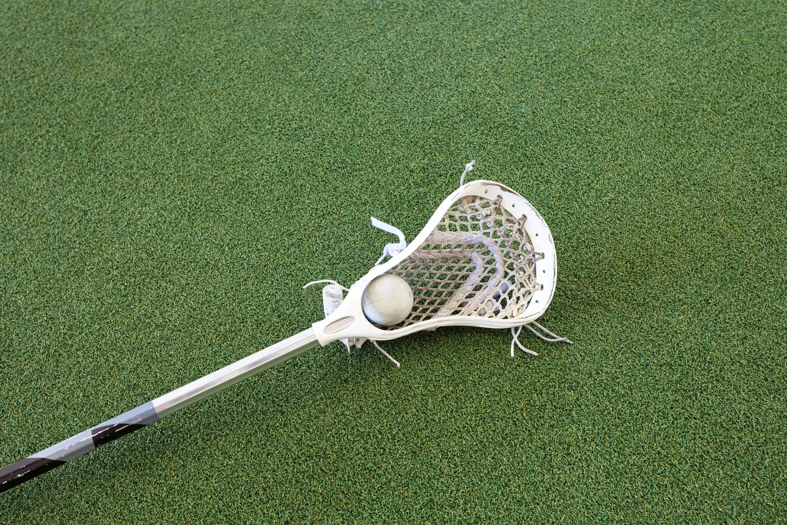 A lacrosse player in full gear sprinting with a stick during training