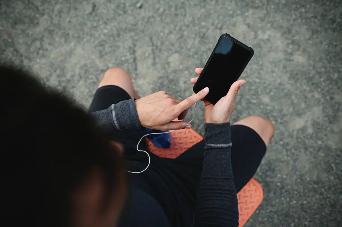 Top view of a sportsman pointing at a blank smartphone screen, a prompt to set a late cancel fee amount in booking