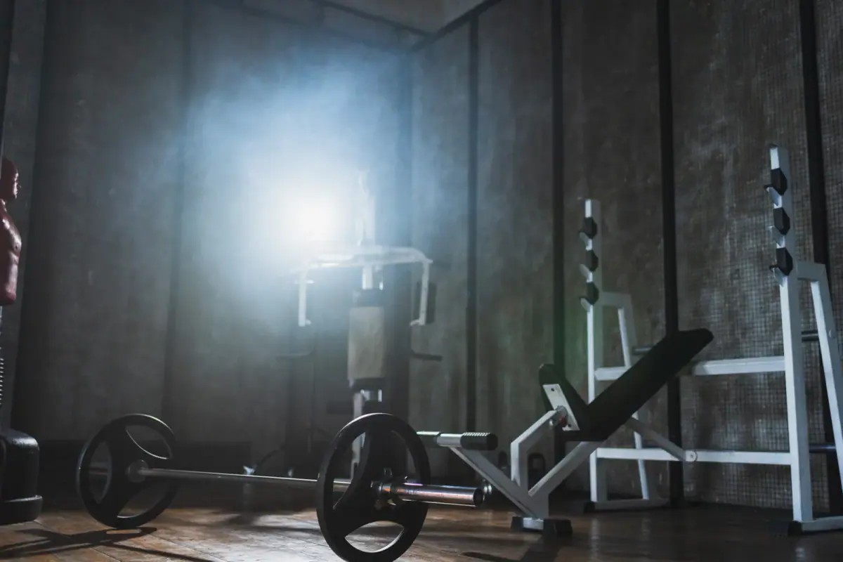 Empty dark gym area with fitness equipment and a barbell, a space where lighting matters when filming a fitness video