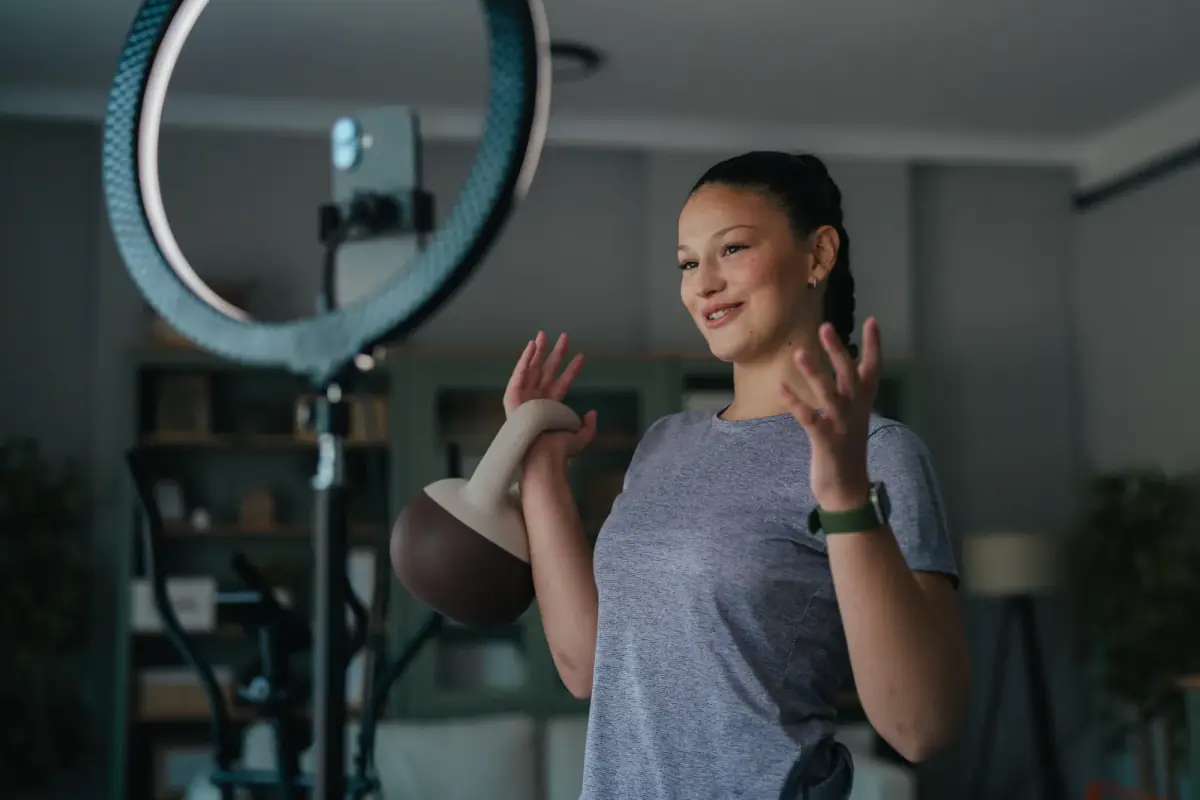 A young woman fitness influencer recording a home workout vlog, where lighting in a small room matters