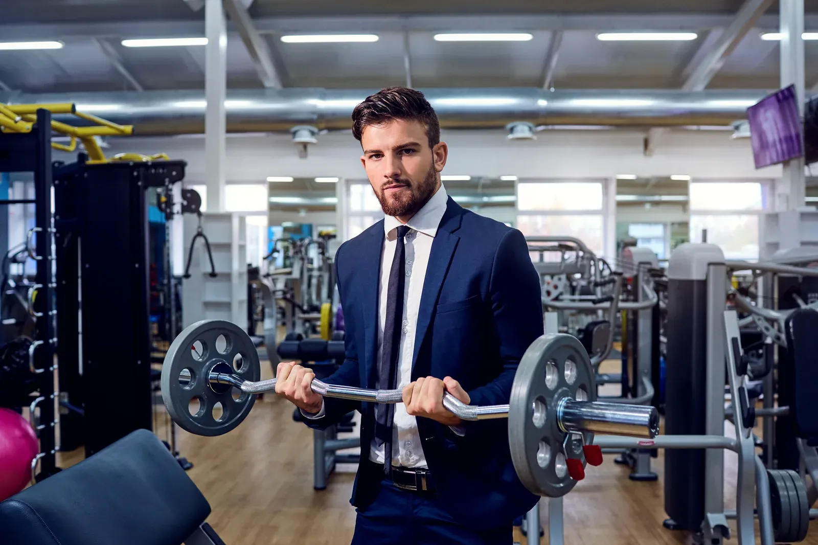 A professional in a suit fitting in a barbell workout