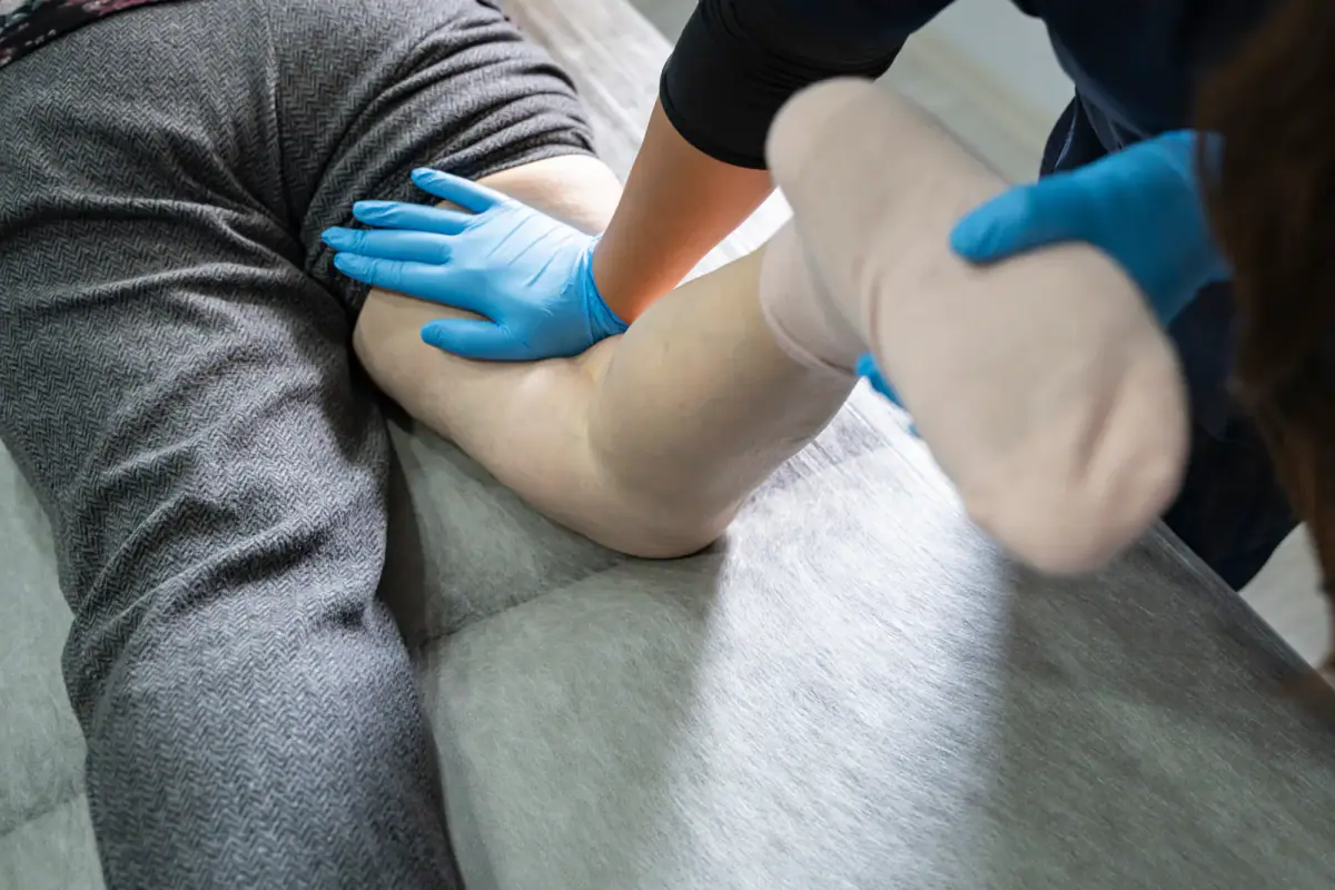 Physiotherapist working with a patient lying on a bed, a care setting for a lymphedema therapist private practice space