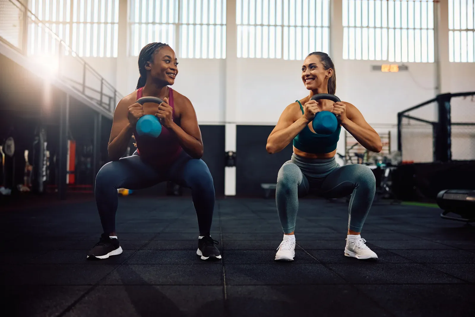 Happy women training with kettlebells during a gym workout