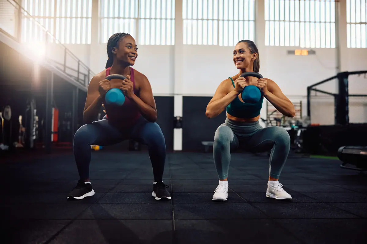 Happy women training with kettlebells during a gym workout