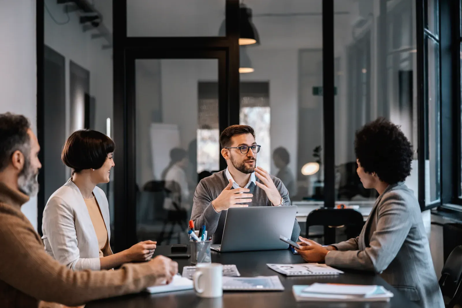 Mentor walking new professionals through next steps around a boardroom table