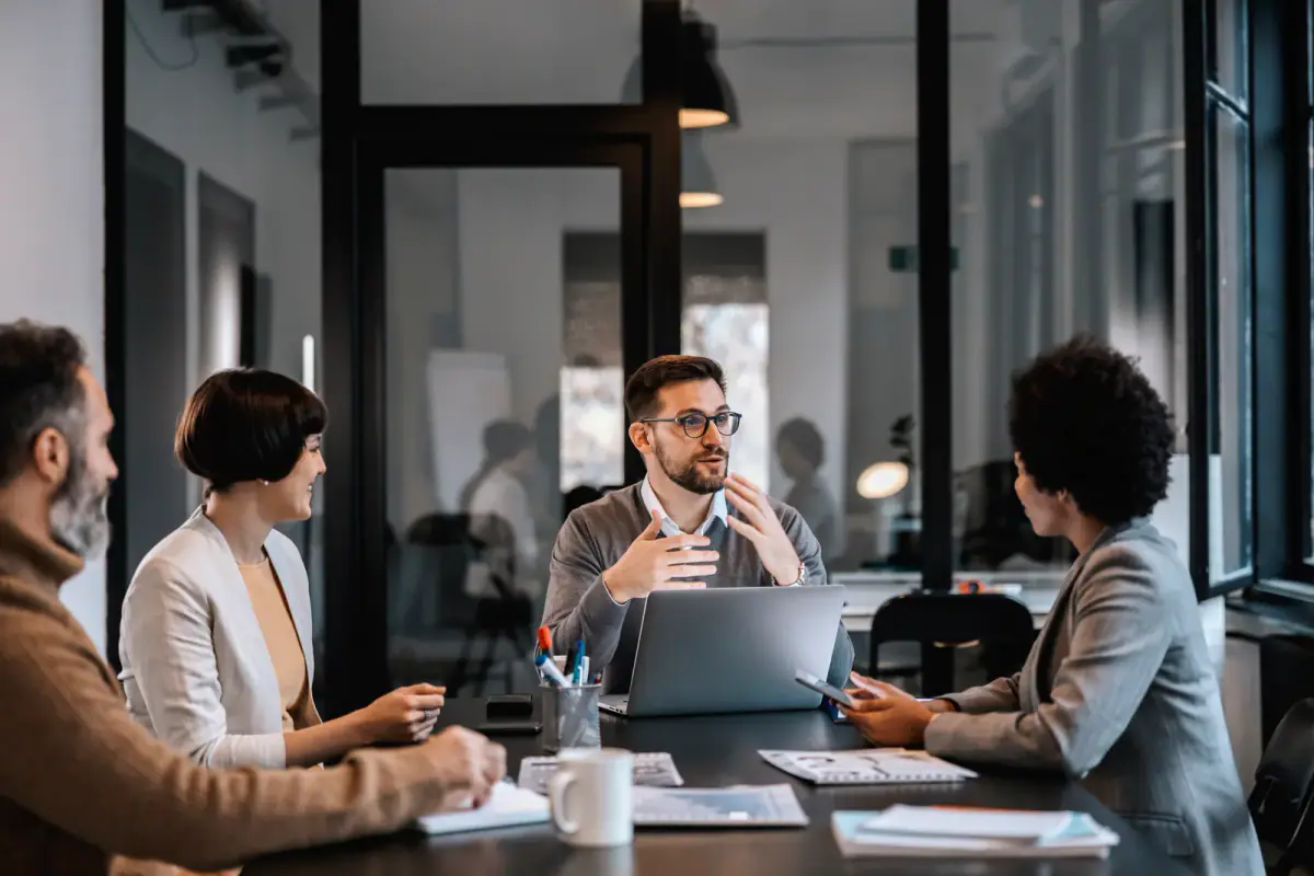Mentor walking new professionals through next steps around a boardroom table