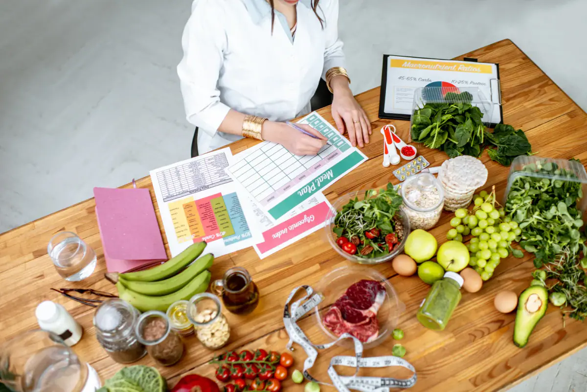 Writing a diet plan at a table filled with healthy food