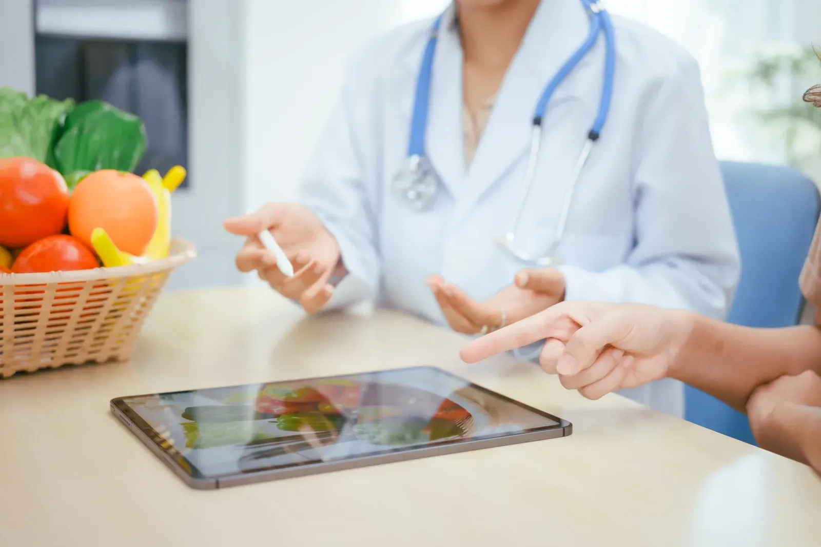 Nutritionist advising a client over a table of fresh fruits and vegetables