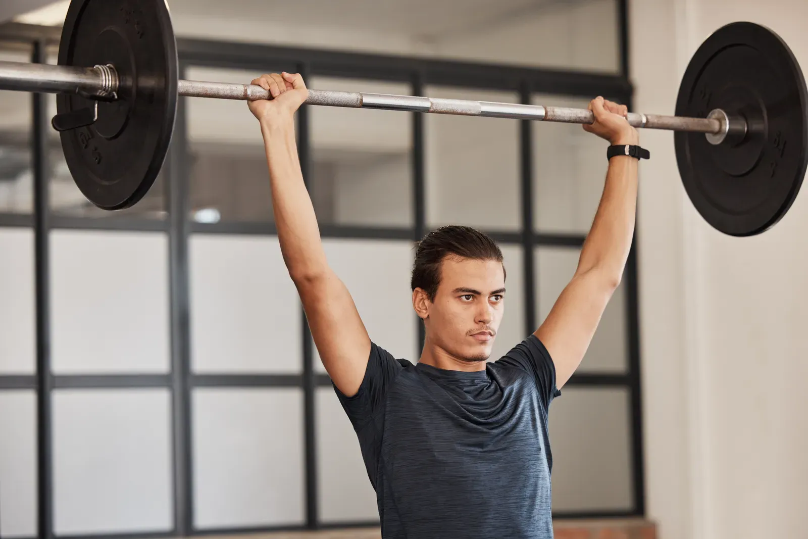 A lifter holding a barbell overhead in a deep squat position