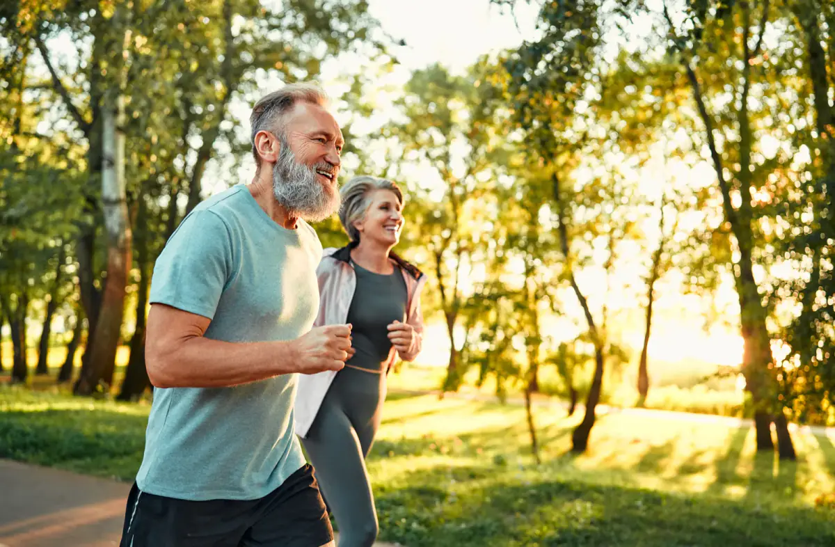 Grey bearded man and an older woman doing outdoor cardio training, a scene from an outdoor personal training business