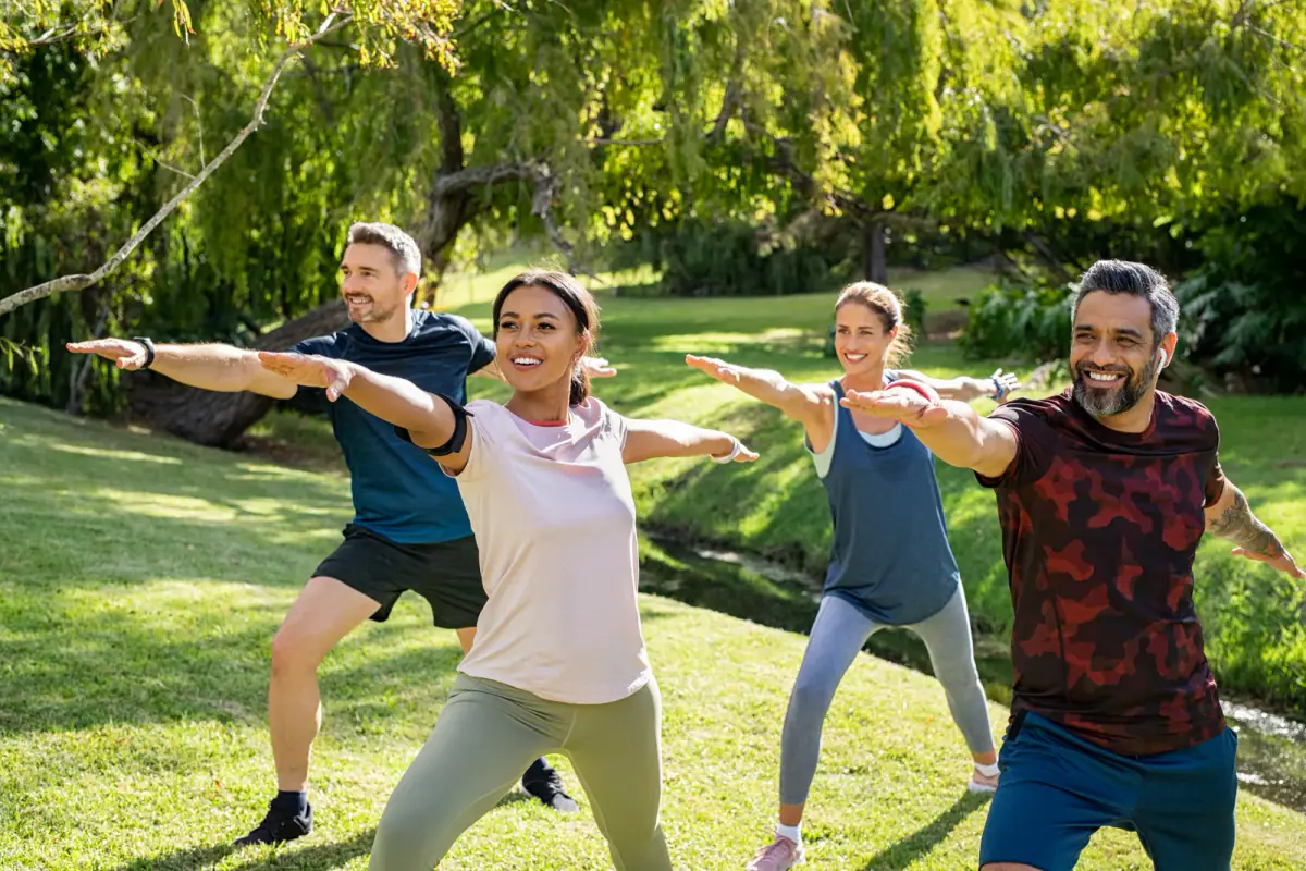Mature men and women stretching at a park after a workout, a group fitness setting where a park permit may be needed
